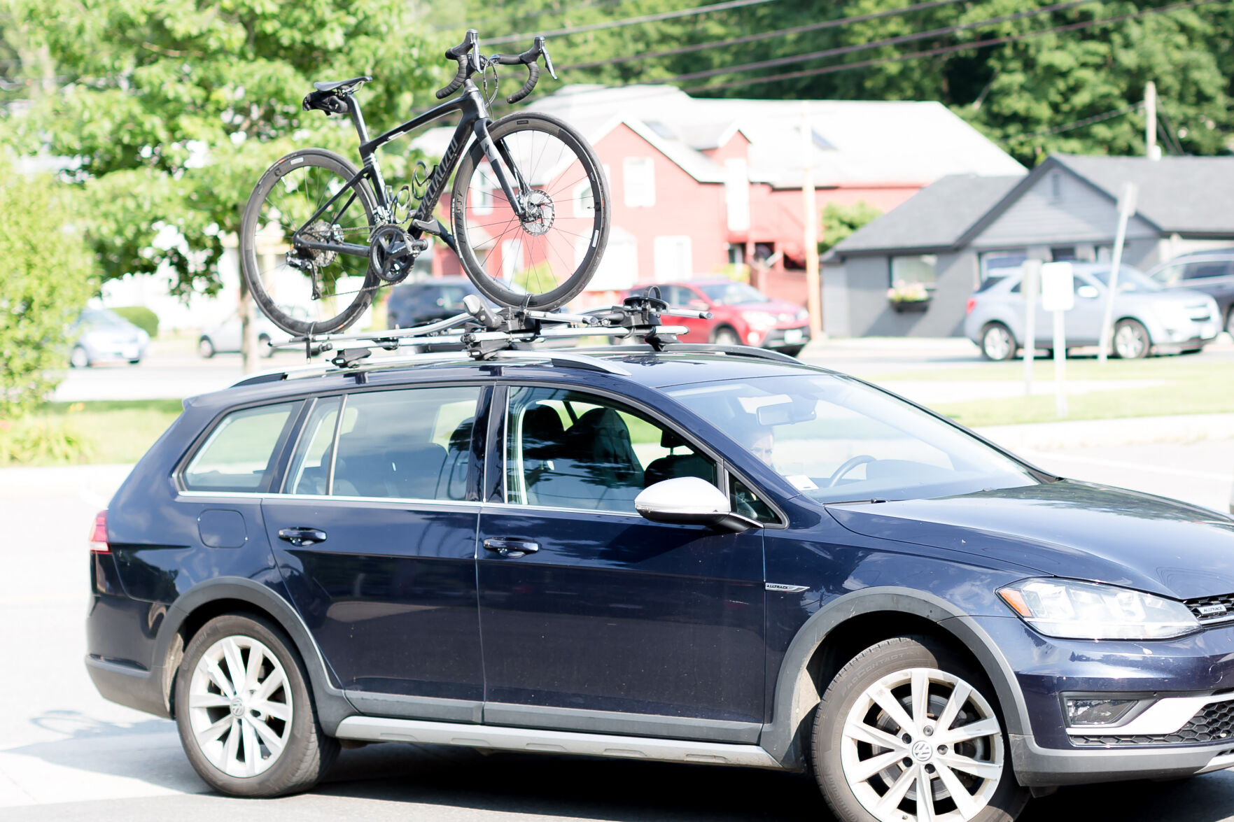 A road bike on top of a blue car with a roof-mounted system.